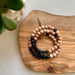 May include: A wooden beaded bracelet with black and natural wood beads. The bracelet is on a wooden surface.