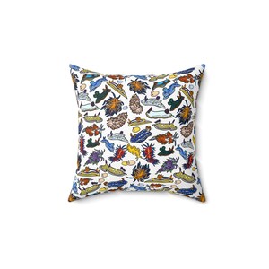 May include: A white square pillow with a colorful pattern of sea slugs. The slugs are drawn in a cartoon style and are various colors, including blue, green, yellow, orange, and red.