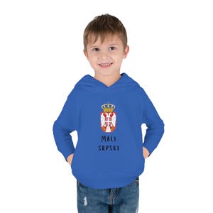 Peut inclure: Un sweat à capuche bleu royal pour enfants avec un blason blanc et rouge, une couronne et le texte "MALI SRPSKI".