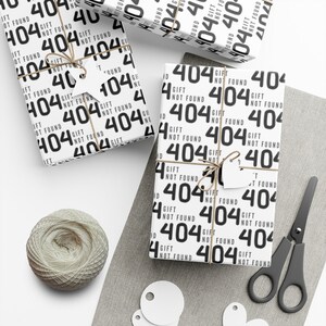 May include: White gift wrap with a repeating pattern of black text that says "Gift Not Found 404". The gift wrap is wrapped around a box with a brown twine bow and a white gift tag.