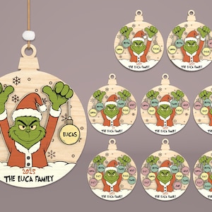 May include: Wooden Christmas ornament featuring the Grinch in a Santa hat, holding baubles with names. The ornament has the text "2025 THE LUCA FAMILY". Additional ornaments with the Grinch and family names are also shown.