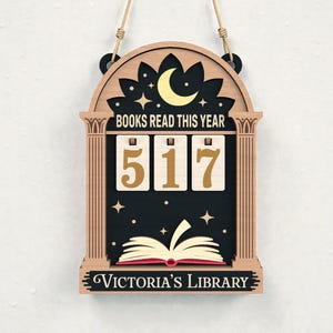 May include: Wooden wall hanging with the text "BOOKS READ THIS YEAR" above the number "517". The design includes a moon, stars, and an open book. The bottom of the sign reads "Victoria's Library".
