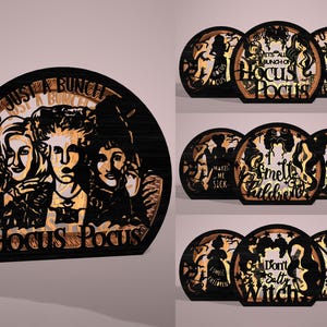 May include: Wooden Hocus Pocus themed decorative signs. The signs feature the Sanderson sisters and various quotes from the movie, such as "It's just a bunch of Hocus Pocus" and "I smell children". The signs are black with a light brown wood grain.