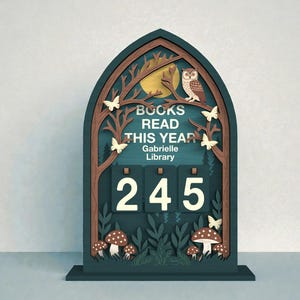 Könnte beinhalten: Ein hölzerner Bücherzähler mit einer Waldszene. Der teal-farbene Rahmen zeigt eine Eule, Schmetterlinge und Pilze. Der Text lautet "BOOKS READ THIS YEAR" und "Gabrielle Library". Der Zähler zeigt die Zahl 245 an.