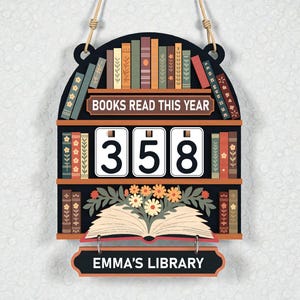 May include: Wooden bookshelf-shaped sign with the text "BOOKS READ THIS YEAR" and "358". The sign has a shelf of books, an open book with flowers, and the text "EMMA'S LIBRARY". It hangs by a rope.