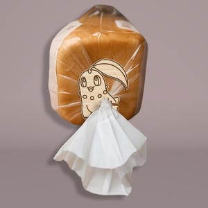 May include: A loaf of bread in a clear plastic bag, sealed with a white paper tie. The bag has a wooden tag with a cartoon character design. The bread is golden brown.