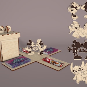 May include: A wooden gift box with a decorative bow on top, surrounded by wooden cutouts of Disney characters. The box is open, revealing candy bars and a box of Nerds candy. Additional character cutouts are displayed.