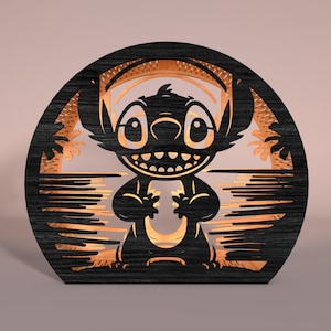 May include: A black and brown wooden layered art piece featuring the character Stitch from Lilo & Stitch. The artwork is in a circular frame with a tropical scene and Stitch's silhouette. The piece has a layered design with a light brown interior.