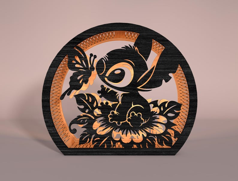 May include: A black and tan wooden decorative piece featuring a cartoon character with large eyes, a butterfly, and floral elements. The design is set within a circular frame with a textured inner border. The piece is likely a decorative item or a light fixture.