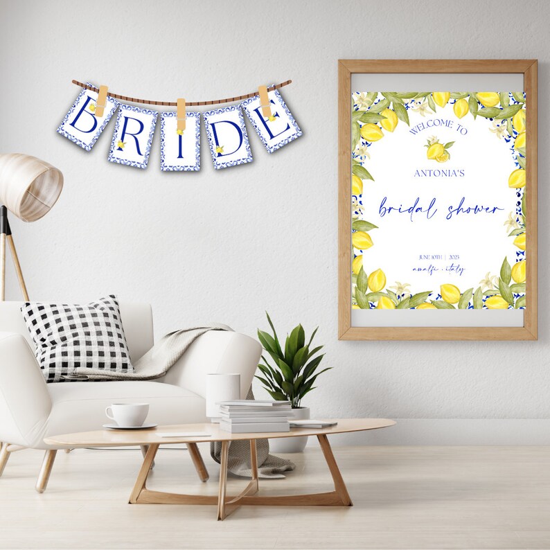May include: A white and blue bridal shower banner with the word "BRIDE" hanging on a string with clothespins. A framed sign with a lemon theme reads "Welcome to Antonia's Bridal Shower June 30th, 2023 Amalfi, Italy".