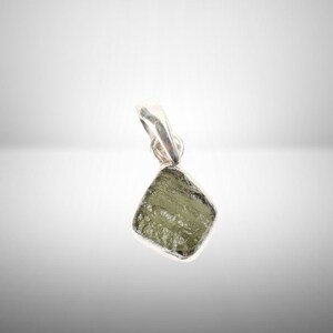 May include: A silver pendant featuring a green, faceted, rough-cut gemstone.