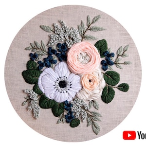 Könnte beinhalten: Stickerei-Blumen-Reifenkunst mit einem Strauß weißer, rosa und pfirsichfarbener Blumen mit grünen Blättern und blauen Beeren. Die Blumen sind in einem realistischen Stil gestickt.
