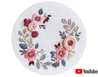 May include: Embroidered floral wreath with pink, red, and white flowers on a beige fabric background. The wreath is made with a variety of stitches and includes leaves in shades of green and gray.