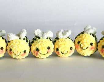 May include: Six small crocheted bee plushies with black and yellow stripes, white wings, and smiling faces.