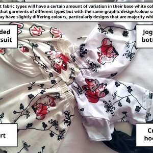 Puede incluir: Se muestran un body con capucha, pantalones de jogging, una falda y una sudadera corta blancos. Cada prenda presenta un patr&oacute;n repetido de una criatura parecida a un zorro rojo y blanco y detalles florales negros. El texto explica las variaciones de color.
