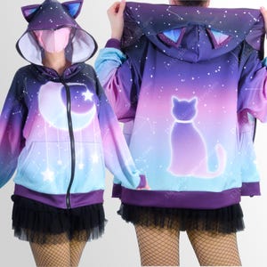 May include: A celestial-themed zip-up hoodie with a crescent moon, stars, and a cat silhouette. The hoodie features a gradient of purple, blue, and pink colours, with cat ears on the hood.