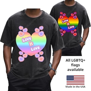 May include: Two black t-shirts with a rainbow heart design that says "Love is Love". The shirts have a vintage wash look. The image also includes the text "All LGBTQ+ flags available" and a US flag.