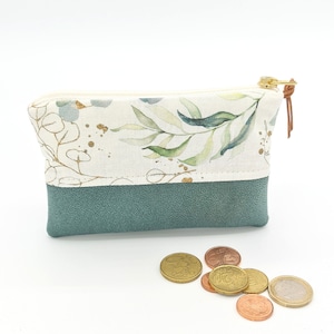May include: A small, zippered pouch with a floral print on the top half and a solid teal bottom half. The pouch is made of fabric and has a gold zipper.