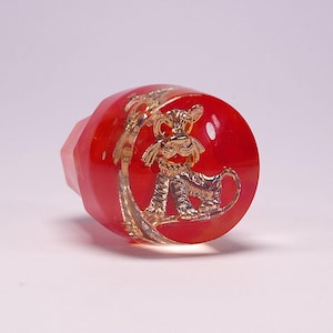 May include: Red glass bottle stopper with a gold tiger design.