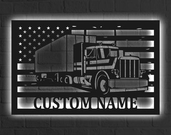 May include: Black metal cutout of a semi-truck driving in front of an American flag with the text "CUSTOM NAME" below.