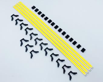 Puede incluir: Vista cenital de tres largas tiras de luz LED amarillo brillante, junto con pequeños clips de montaje y conectores negros. Los componentes están dispuestos sobre una superficie blanca, listos para la instalación.