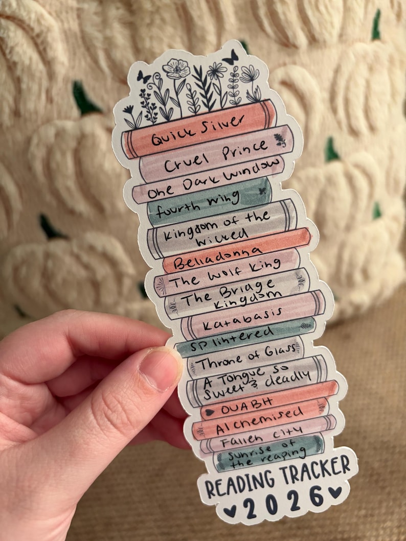 May include: A sticker in the shape of a stack of books, with titles like "Quick Silver" and "Cruel Prince." The sticker has a floral design at the top and reads "Reading Tracker 2026."