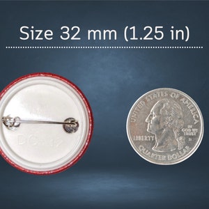 May include: A 32 mm (1.25 inch) button with a red border and a white centre. The back of the button has a safety pin and the number "DO182" printed on it.