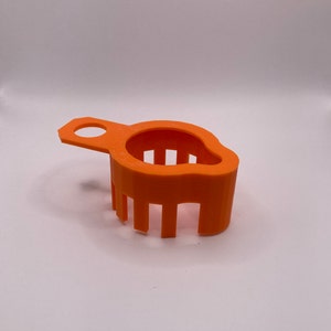 May include: Orange plastic strainer with a handle. The strainer has a rounded shape and a series of vertical bars.