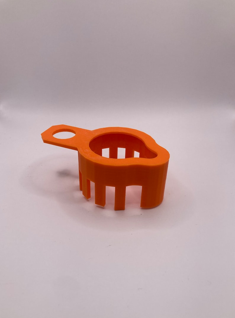 May include: Orange plastic strainer with a handle. The strainer has a rounded shape and a series of vertical bars.