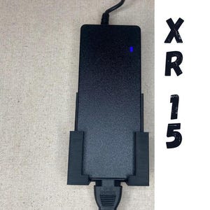 Op de afbeelding: Zwarte stroomadapter met een blauwe indicatorlamp en een stroomkabel. De adapter is gemarkeerd met "GF-23" en "WARNING".