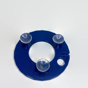 May include: A blue plastic ring with three suction cups attached. The ring has a small hole on the side.