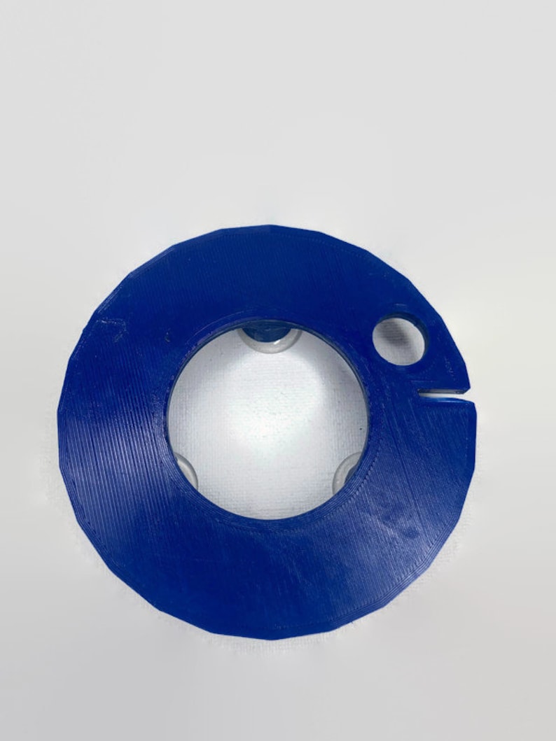 May include: A blue plastic ring with a hole in the center and a small hole on the side. The ring has a textured surface.