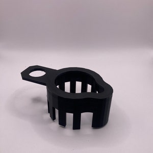 May include: A black plastic 3D printed tool with a handle and a series of vertical slots. The tool is designed to hold a round object.