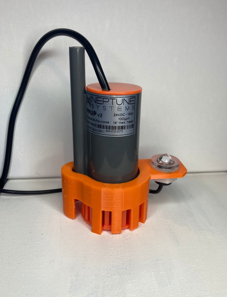 May include: A grey and orange water pump with a black cord. The pump has a label that reads "Neptune Systems PHUP v2 24VDC-19W 100gph 14' max. head MOT RUN DRY) 400-012-2273".