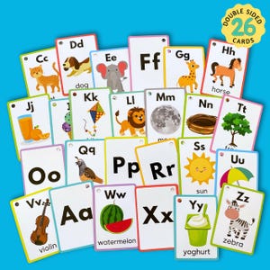 May include: A set of 26 double-sided alphabet flash cards featuring colorful illustrations of animals, objects, and letters. The cards are designed for children learning the alphabet.