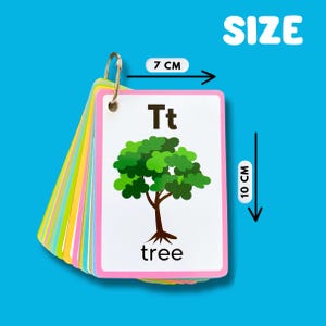 May include: A set of alphabet flash cards with a pink border. The card shown features the letter "T" and a picture of a green tree with the word "tree" written below. The cards are 7 cm wide and 10 cm tall.