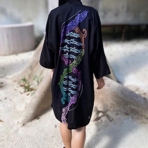 Op de afbeelding: Zwarte kimono-achtige robe met een kleurrijk, abstract ontwerp op de rug. Het kunstwerk toont golvende lijnen in tinten blauw, paars, groen en oranje. De robe heeft wijde mouwen en een relaxte pasvorm.