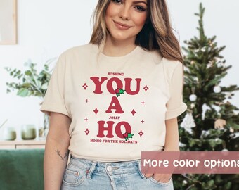 May include: A beige t-shirt with a red graphic that says "Wishing You A Jolly Ho Ho for the Holidays".