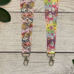 May include: Two colorful lanyards with unicorn and rainbow designs. Each lanyard has a silver metal clip.
