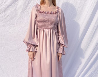May include: A long, blush pink satin dress with a square neckline and puffed sleeves. The dress has a smocked bodice and a flowing skirt.