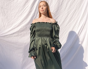 May include: A long, dark green off-the-shoulder dress with long sleeves and ruffled cuffs. The bodice is smocked, and the skirt flows to the floor. The text "Gorgeous Green" is at the bottom of the image.