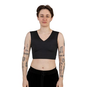 May include: A black sleeveless crop top with a V-neckline. The top is made of a soft, stretchy fabric and has a relaxed fit.