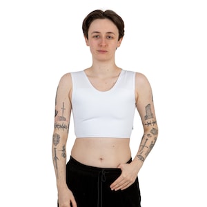 May include: A white, sleeveless compression top with a scoop neck. The top is made of a smooth, stretchy fabric.