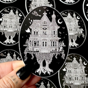 May include: Black and white illustration of a spooky house with an eye on the front, perched on the legs of a bird. The house is surrounded by trees and vines.