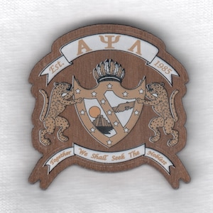 May include: A brown wooden crest with a white shield and gold accents. The shield features a sun, a pyramid, and a handshake. Two brown jaguars flank the shield. The crest is surrounded by a brown banner with the text "AΨΛ Est. 1985 We Shall Seek The Noblest Together".