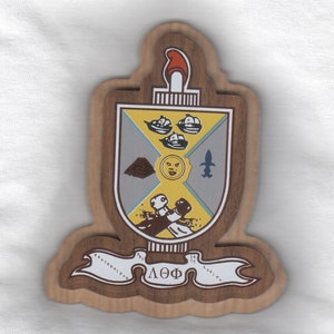 May include: A wooden plaque with a shield-shaped design featuring a yellow sun, a pyramid, a fleur-de-lis, and three ships. The shield is surrounded by a banner with the text "ΔΟΦ" and the dates "1975" and "1900".