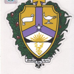 May include: A sticker featuring the Alpha Kappa Lambda Fraternity crest. The crest is a shield shape with a gold and purple color scheme, surrounded by green foliage. The text "Alpha Kappa Lambda Fraternity" and "AKA" are also visible.