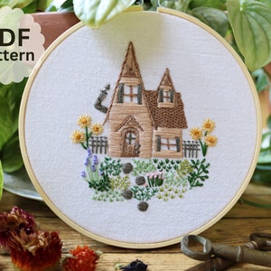 May include: Embroidered hoop art featuring a brown house with a white door and windows, surrounded by green foliage and yellow flowers. The text "PDF pattern" is visible in the top left corner.