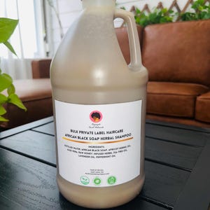 Pode incluir: Uma garrafa grande de plástico bege de champô herbal de sabão preto africano com tampa e alça brancas. O rótulo lista ingredientes, incluindo água destilada, sabão preto africano e aloe vera.