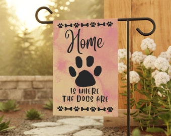 Può includere: Una bandiera da giardino rosa e gialla con un'impronta di zampa nera e il testo "Home is where the dogs are".